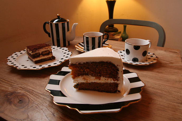 카페 해크니의 당근 케이크를 촬영한 사진. 테이블 위에 올려진 두 개의 접시에는 당근 케이크 한 조각과 티라미수가 각각 놓여 있다. 케이크 접시 뒤편에는 줄무늬와 도트 무늬의 커피잔과 주전자가 놓여 있다.