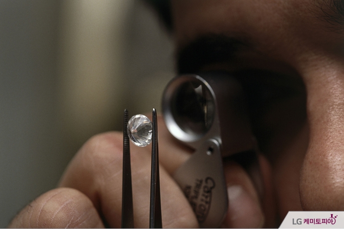 한 남성이 현미경으로 다이아몬드를 보고 있다.