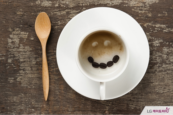 비어있는 커피 잔 속에 커피콩들이 웃는 얼굴을 형상화하고 있다.