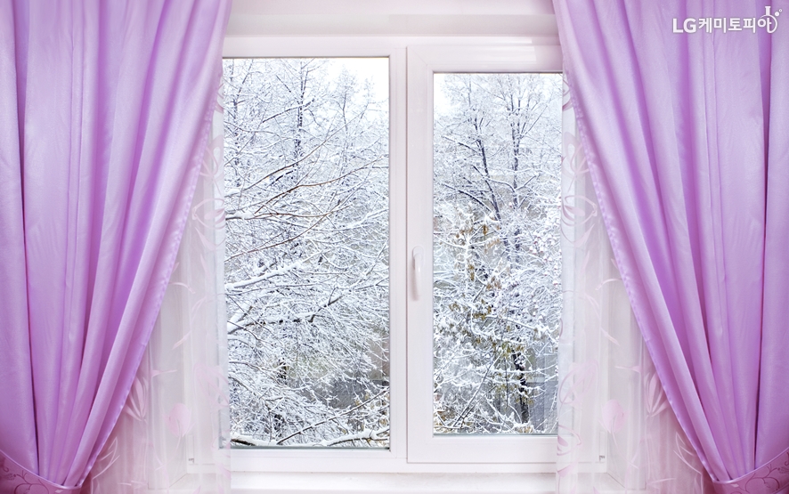 겨울 눈쌓인 바깥이 보이는 창문 안에 도톰한 커튼이 쳐져 있다.