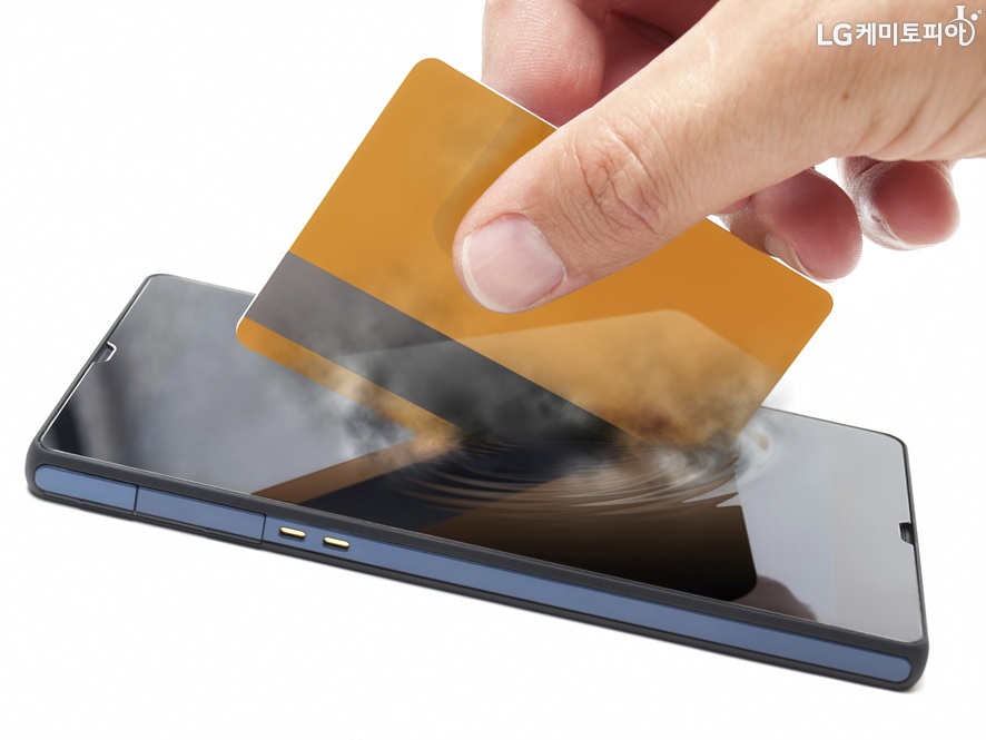 휴대폰 안에 신용카드를 삽입하고 있는 이미지컷. 신용카드가 모바일에 심겨졌다는 의미를 반영하고 있다.