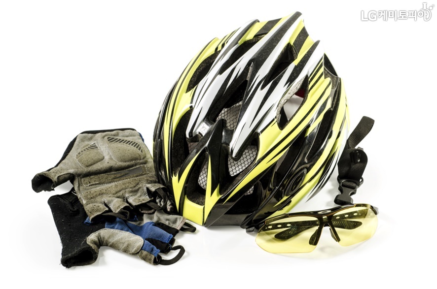 노란색과 검정색이 조합된 자전거 헬멧과 장갑 그리고 노란색 선글라스가 함께 있는 사진.