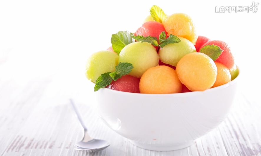 알록달록 동그랗고 차가운얼음 아이스크림이 과일과 섞여 하얀 그릇에 담겨 있다.