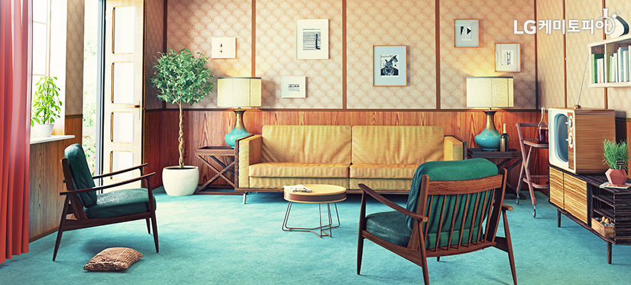 인테리어-창문이 있는 거실에 쇼파와 의자가 있고 노랑색 벽지 위에 액자들이 걸려 있다.