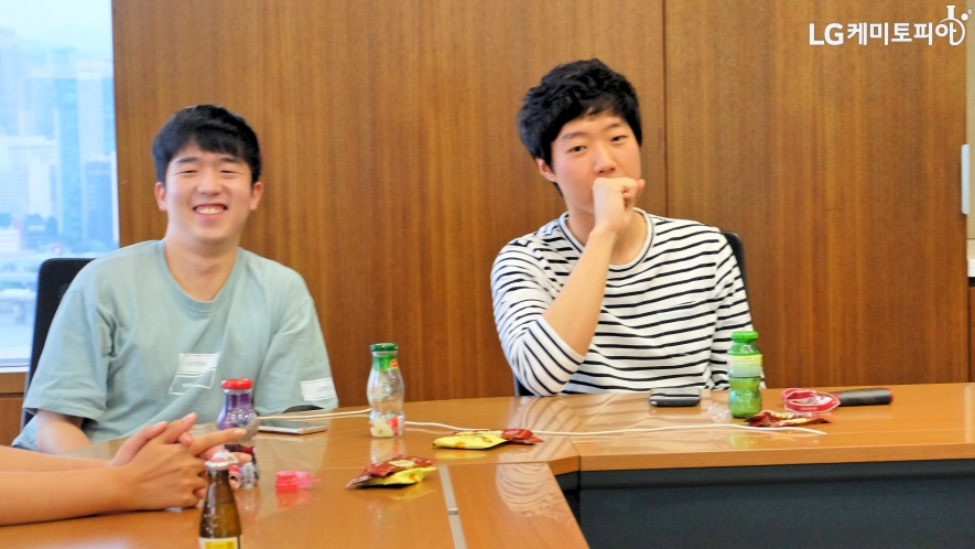LG화학 대학생 에디터 3기, 양태현 에디터와 진재훈 에디터가 테이블에 앉아 웃고 있다.