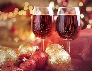 붉은색 테이블 위에 크리스마스 느낌의 장식이 되어있고, 와인잔 2잔에 레드와인이 있다.
