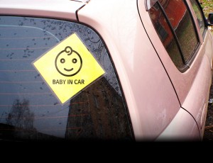 자동차 뒷유리에 Baby in car 표시 스티커가 붙어 있다.