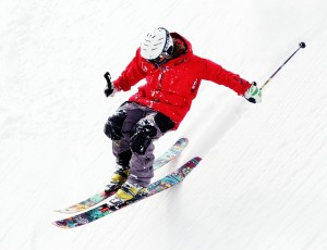 스키장비를 완장한 사람이 스키를 타며 눈 쌓인 스키장을 내려오고 있다.