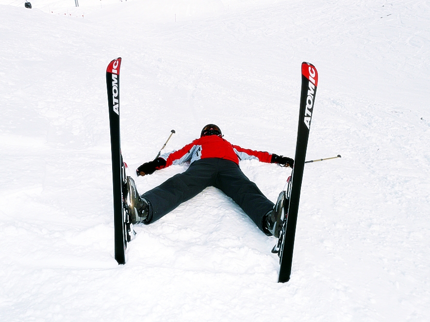 눈 쌓인 땅 위에 스키 장비를 착용한 사람이 엎드려서 누워있다.