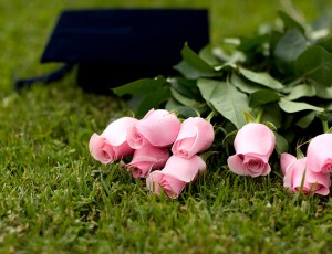 잔디 위에 분홍색 장미꽃 8송이와 학사모가 놓여있다.